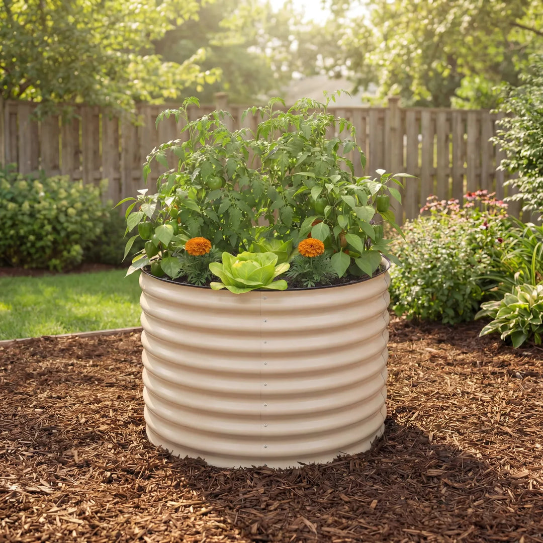 Beige round raised metal planter with plants in a garden setting