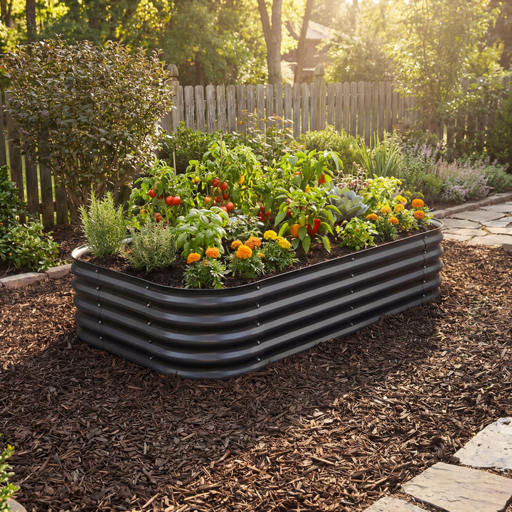 Black wide short raised garden bed with vegetables and flowers in a backyard setting